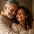 Um casal de longa data abraçado, dividindo os fones de ouvido