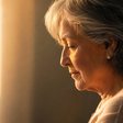 Uma senhora de perfil, olhando para baixo na luz da janela